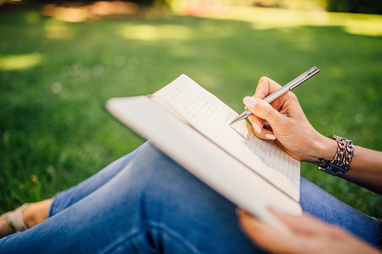ghostwriter woman writing in a notebook at the park